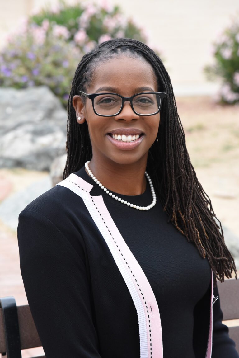 Professional headshot by Laura Voight: smiling woman with braids, glasses, and a pearl necklace
