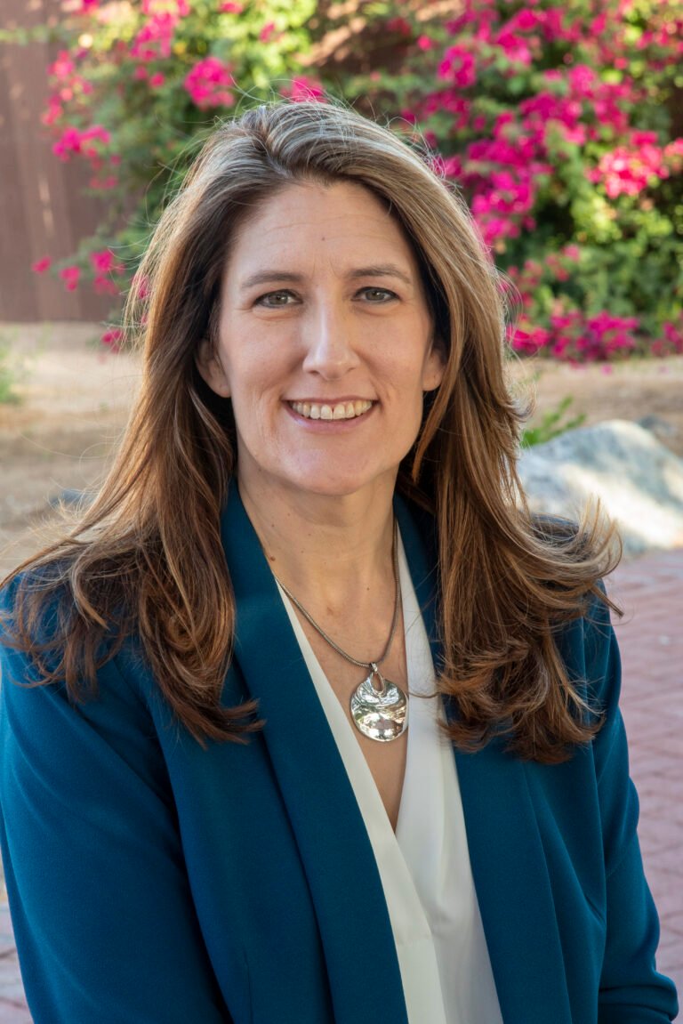Outdoor headshot by Laura Voight: woman in a teal blazer smiling in front of blooming bougainvillea, Phoenix