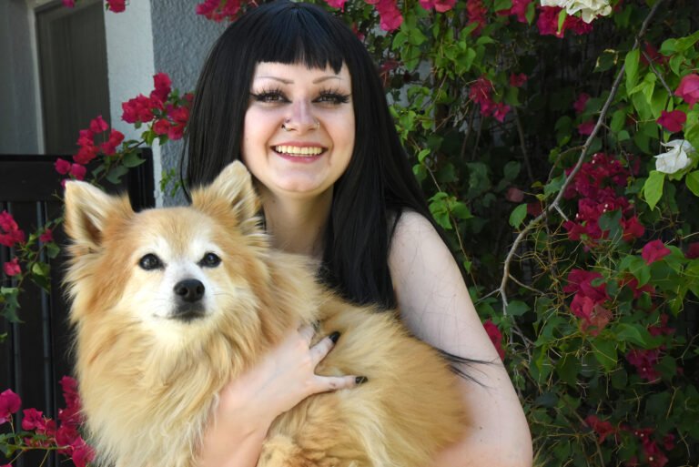 Fun portrait by Laura Voight: young woman holding her pomeranian dog outdoors