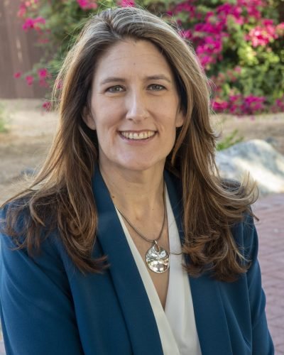 Outdoor headshot by Laura Voight: woman in a teal blazer smiling in front of blooming bougainvillea, Phoenix